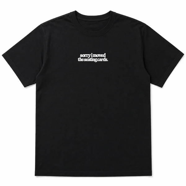 flat lay mockup of a heavyweight tee in black and white, front view, with the printed line sorry i moved the seating cards across the chest